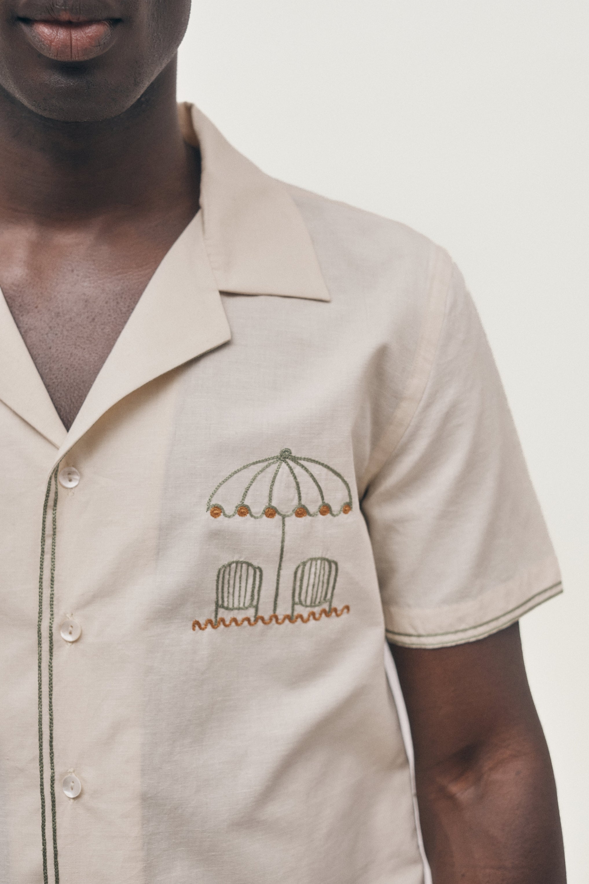 Beige shirt with embroidered design on a plain background