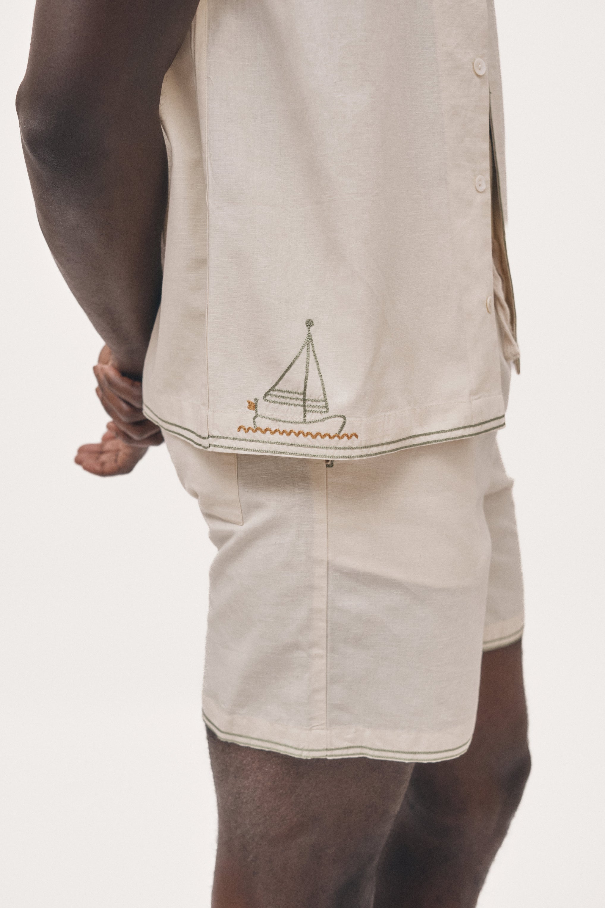 Beige shirt with sailboat design and shorts on a white background
